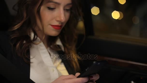 車の後部座席に乗る時に携帯電話で魅力的な女性のテキスト メッセージ — ストック動画