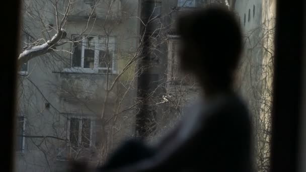 Kadın pencere kenarında oturan ve yürekli kırık pencereden dışarı bakarak — Stok video