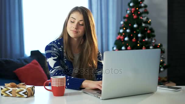 Chica sosteniendo caja de regalo trabajando en hristmas notebook.C y feliz año nuevo . — Vídeos de Stock