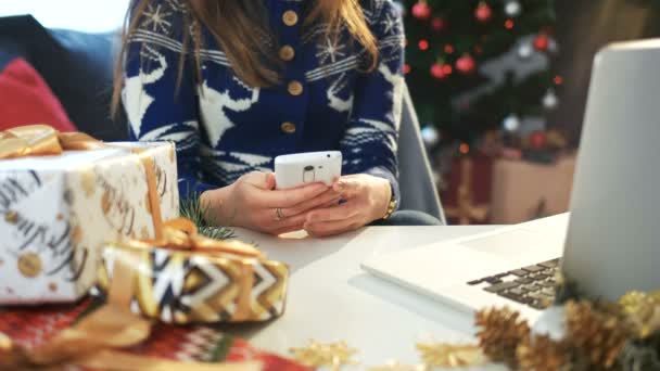 Молодая девушка пишет рождественские пожелания со своего смартфона. Новогодняя вечеринка — стоковое видео