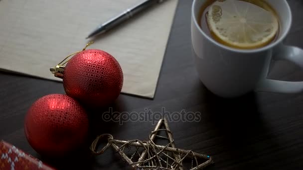 Vánoční čaj s hračkami, hvězdy a Poznámka: kniha o hnědé dřevo stůl. Vánoční dekorace. Pohled shora. — Stock video