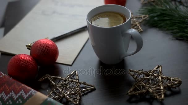 Рождественский чай с елкой, красными игрушками, звездами и гирляндой на коричневом деревянном столе. Рождественское украшение. Вид сверху . — стоковое видео