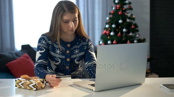 Vrouw online winkelen op laptop met een credit card op de achtergrond van de kerstboom. — Stockvideo