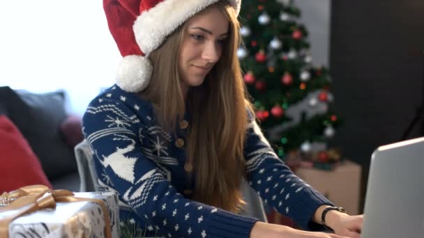 带上笔记本电脑和圣诞树背景在客厅里喝咖啡的朋友微笑年轻女子聊天. — 图库视频影像