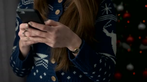 Jeune femme mains tapant sur tablette sur fond de fenêtre avec arbre de Noël. Gros plan .