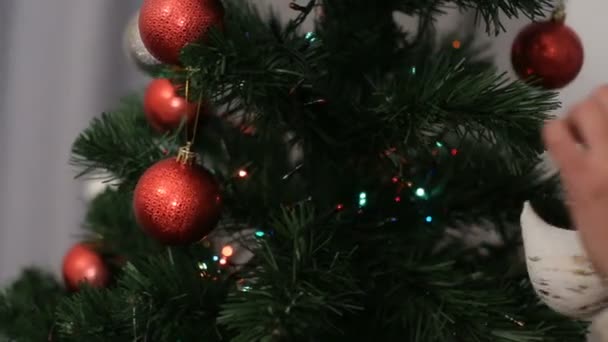 Junge Frau mit Weihnachtsmann-Hut schmückt den Weihnachtsbaum auf Bokeh-Hintergrund. — Stockvideo