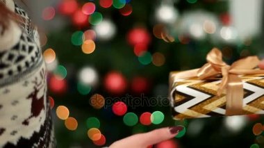 Genç adam Noel ağacı arka plan ışığı ile kız arkadaşına bir Noel hediyesi veren eller. Yakın çekim.