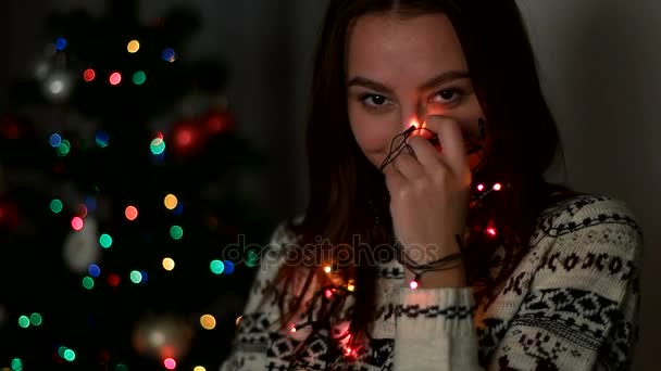 Portrait of attractive young woman smiling and posing with christmas light on camera. Close up. — Stock Video