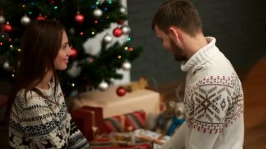 Christmastree bokeh ışık ile yakın yerdeki siting genç kadına hediye vermek güzel adam.
