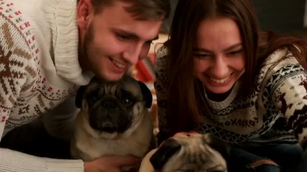 Attraktive junge Frau macht Selfie mit jungem Mann und Mops-Hund in der Nähe des Weihnachtsbaums. Nahaufnahme. — Stockvideo