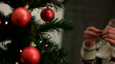 Bir Noel ağacı kırmızı ve gümüş renkli kazak oyuncaklar dekorasyon eller genç kadın. Yakın çekim.