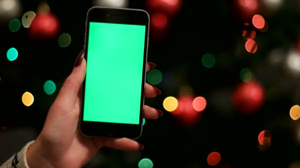 Donna mano tenendo smart phone con schermo verde su ghirlande bokeh sfondo. Chiudete. Chiave cromatica . — Video Stock