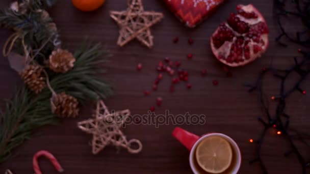 Bovenaanzicht van de kerst. Kerstdecoratie, Kerstverlichting, thee en granaatappel op houten tafel. Schot van bovenaf — Stockvideo