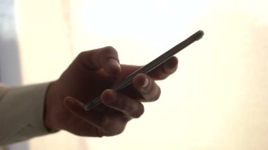 Erkek el kadar akıllı telefon tutarak kapatın. Pencere duran cep telefonu kullanan adam. Dokunmatik ekranda dokunarak. Siluet