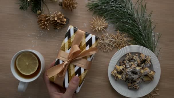 Man putting christmas present on a wooden table with christmas decoration. Top view. Close up. Cozy Christmas mood — Stock Video