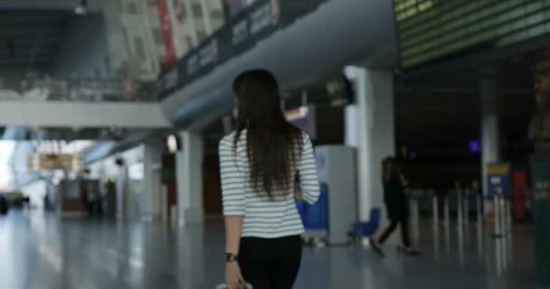 Attraktiv kvinna tittar på tidtabell avgång styrelsen train station — Stockvideo