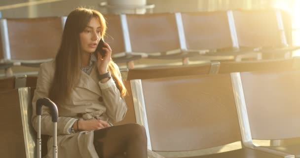 Geschäftsfrau im beigen Mantel telefoniert am Flughafen — Stockvideo
