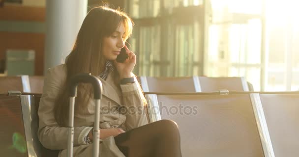 Mulher de negócios em casaco bege fala ao telefone no aeroporto — Vídeo de Stock