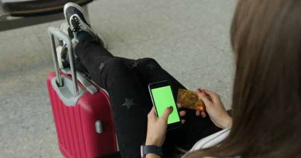 女の子グリーン スクリーンのスマート フォンを使用。オンライン ショッピング。動揺している彼女のフライトを待っているバックパックと国際空港で荷物を運ぶ美しい若い観光客女の子. — ストック動画