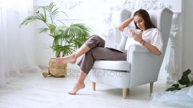Kahve veya çay içme ve sandalyede, rahatlatıcı güzel kız bir kitap okuma