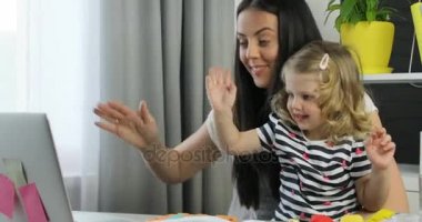 Anne ve babasıyla dizüstü ev zemin üzerine masaya siting üzerinde görüntülü sohbet sahip dauther. Kapalı.