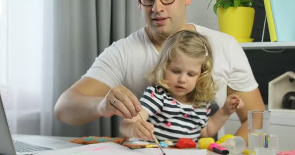 Jovem caucasiano com óculos e sua filha bonita com cabelo encaracolado loiro vídeo conversando com a mãe. Interior . — Vídeo de Stock