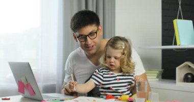 Gözlük ve onun dauther boyalar üzerinde ev arka plan kullanarak sarı kıvırcık saçlı çizim ile çekici genç adam. Kapalı.