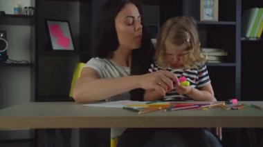 Keçeli kalem masaya oturma zemin üzerine annesiyle siting ile çizim sarışın kıvırcık saçlı küçük kız. Kapalı.