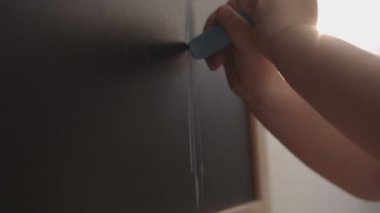Elinde bir şey mavi tebeşir kullanarak bir tahtada çizim beyaz küçük kız portresi. Kapalı.