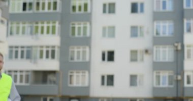 Genç Beyaz Oluşturucusu'nda beyaz Miğferde koyarak ve etrafa bitmemiş inşaat zemin üzerine yeşil yelek. Açık.