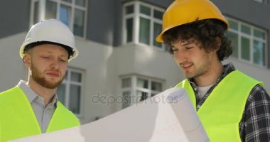 Kask ve özel kıyafetler oluşturma ve bu konuda konuşmak çizim analiz iki beyaz inşaatçılar portresi. Açık.