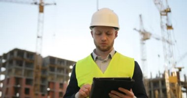 Beyaz kask ve tablet için iş kullanma inşaat sahasında yeşil yelek inşaat mühendisi. Açık.