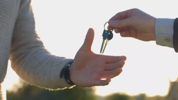 Hands of business man and client. Business man giving keyses to client and shaking hand on nature background. Close up. Oudoor. — Stock Video