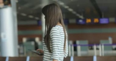 Lounge bölgesine gelen ve uluslararası havaalanında bankta oturmuş tablet ile çekici genç kadın.