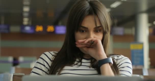 Jonge aantrekkelijke vrouw geeuwen tijdens het gebruik van de laptop, wachten haar vlucht op de internationale luchthaven. Close-up. — Stockvideo