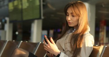 Akıllı telefon ve alma selfie havaalanında kullanan çekici kadın. Yan görünüm.