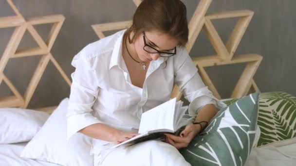 Jeune femme béatifique se détendre à la maison tout en lisant sur le lit . — Video