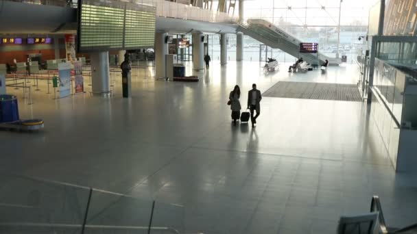 Atracttive unga par i kärlek med bagage promenader genom den internationella flygplatsen. — Stockvideo