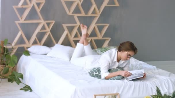 Mladá krásná žena v pohodlí domova při čtení na posteli doma. — Stock video