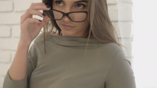 Ritratto di giovane donna attraente con occhiali in possesso e sorridente sulla macchina fotografica . — Video Stock