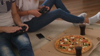 Pizza yemek ve video oyun evde oturma odasında oynarken duygusal genç çift laughting ve having fun.