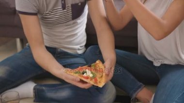 Genç mutlu adam ve yerde evde oturan ve lezzetli pizza yemek kadın.