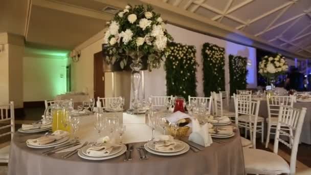 Close-up shot van ingerichte witte tafels voor een trouwdag met witte roos in de vaas. Dolly schot. — Stockvideo