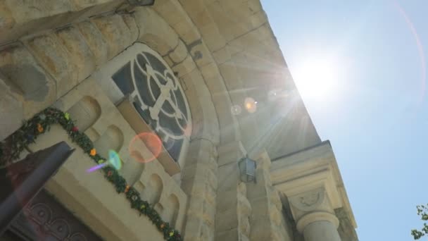 Uitzicht vanaf de onderkant van de kerk fasad op de blauwe hemel met zonneschijn achtergrond. — Stockvideo