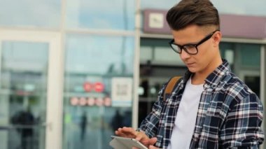 Şık gözlük için uçağını beklerken modern havaalanında tablet kullanarak beyaz adam portresi.