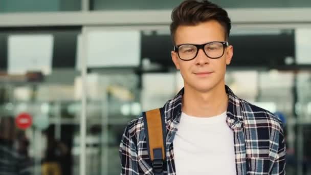 Porträtt av ung attraktiv man i glas gångavstånd till moderna flygplatsterminalen för hans flygning. — Stockvideo