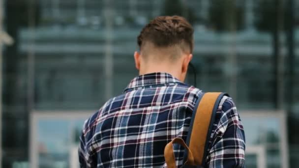 Portret shot van jonge man wandelen naar de moderne luchthaven terminal voor zijn vlucht. Uitzicht vanaf de achterkant. Close-up. — Stockvideo