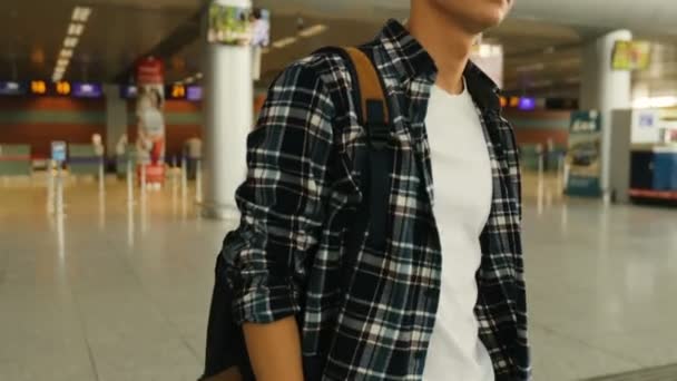Portrait of young handsome man in the glasses with the baggage walking from the plane in the modern airport terminal. Dolly shot. Close up. — Stock Video