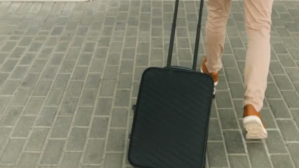 Close-up shot van de benen van de man met de bagage die lopen naar de luchthaventerminal. Dolly schot. — Stockvideo