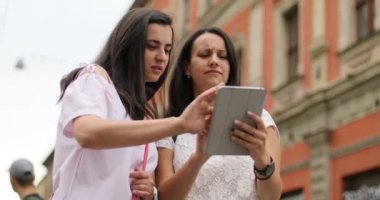 Ziyaret etmek için ilginç bir yer bulmak için tablet cihaz internette sörf kız arkadaşları. Açık havada kızlar.
